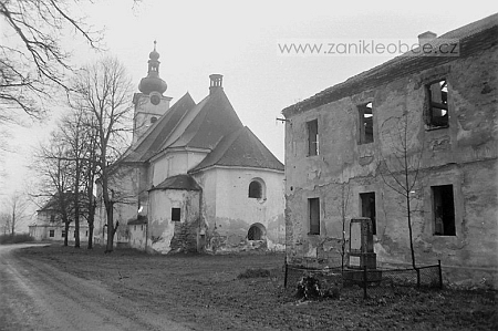 Na snímku z roku 1991 je zachycena vpravo škola s památníkem padlých, vlevo za kostelem pak budova fary