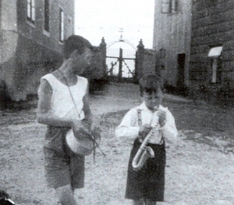 Vstup na hřbitov v Kapličkách mezi školou a farou, vepředu Tassilo a Günther Bitzanovi na snímku pořízeném jejich otcem 24. června roku 1935