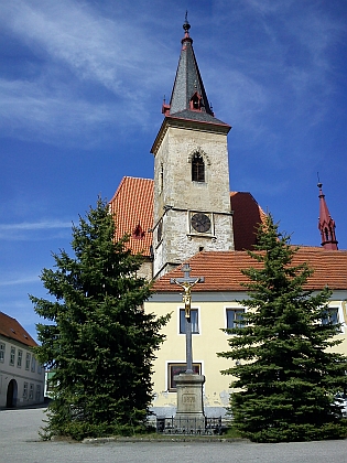 Za křížem s pozlacenou sochou Krista stojí chvalšinský gotický kostel sv. Maří Magdaleny s nádherným interiérem