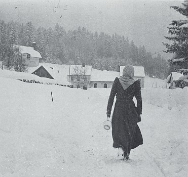 Žena se skleněným džbánem a v šátku uvázaném "na český způsob" (většina lidí sem přicházela za prací z Čech) cestou ke sklářské hospodě v Buchenau na snímku z roku 1921