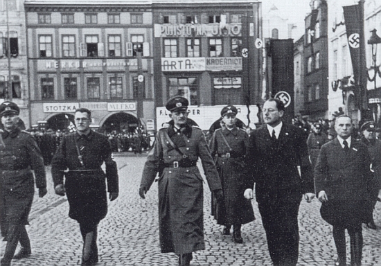 15. března 1939 tu kráčí před českobudějovickou radnicí, po jeho pravici generál von Weichs a Hans Westen, za nimi patrno zakrytí sochy Augusta Zátky drapérií s hákovým křížem