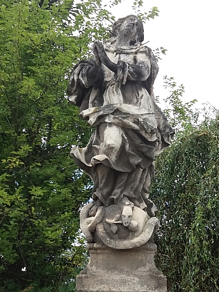 Socha Panny Marie Immaculaty z roku 1727 u kostela v Nových Hodějovicích (z původního místa u Plavské silnice byla ke kostelu Panny Marie Královny andělů /postavenému roku 1938/ přenesena v roce 1940)