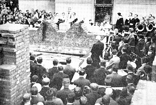 Měšťanská škola v Poběžovicích se zrcadlí v hladině městského rybníku - dodnes slouží svému účelu a najdeme na ní i datum položení základního kamene 3. května 1936, které provedl právě prelát Feierfeil