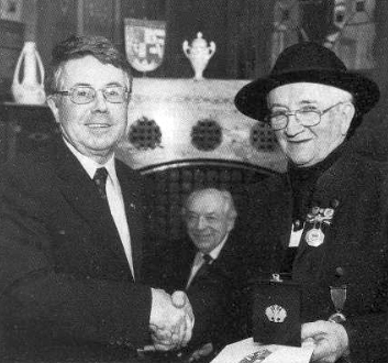V klobouku chebského rodáckého kroje přijímá gratulaci zástupce bavorské vlády k udělení záslužného kříže se stuhou od německého spolkového prezidenta Raua