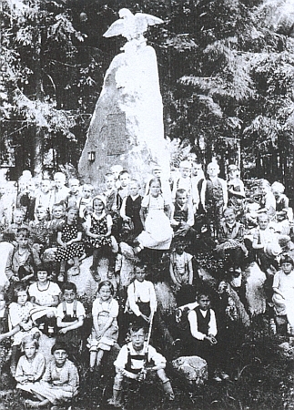 Děti z obecné školy v někdejších Kapličkách jsou tu při školním výletě zachyceny před památníkem padlých v první světové válce v někdejších Nových Domcích