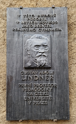 Pamětní deska s jeho podobou a jménem na budově bývalého gymnázia v Prachaticích, Husova ulice čp. 109