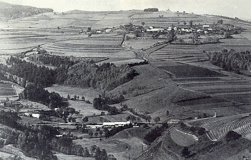 Pohled zachycující dole vpředu jeho rodnou ves Branná (Pramles) uprostřed s někdejším hamrem, nahoře vpravo nad ní pak Nahořany (Hochdorf)