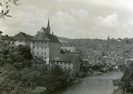 Na pohlednici Josefa Wolfa je vlevo zachycena budova někdejšího německého gymnázia v Českém Krumlově (dnes zde sídlí muzeum)