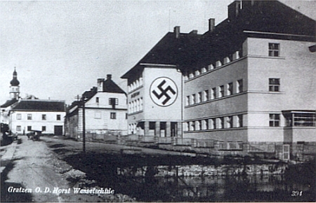 ... a podobný záběr z doby druhé světové války se symbolem nacistické zvůle na tehdy německé "Horst-Wessel-Schule", po němž donedávna svítil na zdi bílý kruh (pohlednice z doby, kdy město patřilo k župě Ober Donau)