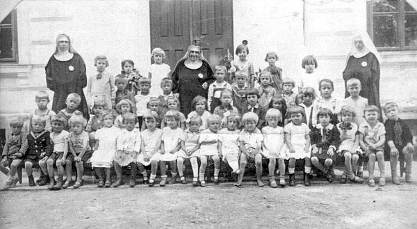 Na snímku dětí z novohradské mateřské školy, spravované řádem servitek, sedí její otec v raném dětském věku sedmý zprava v prvé řadě