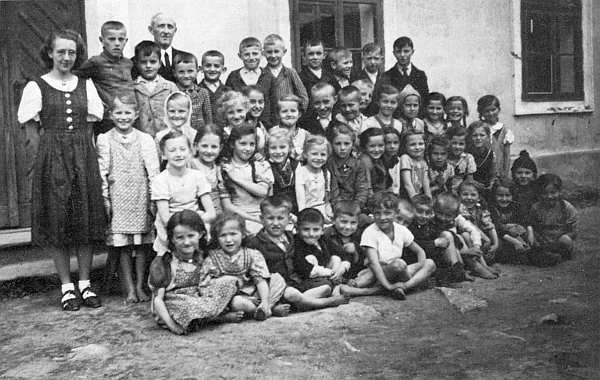 Pan řídící Hans Süka, zde s učitelkou nám neznámého jména a s dětmi ročníku narození 1934/35,
na snímku z Hojné Vody válečného roku 1942